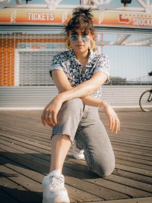 A trendy young woman in vibrant sunglasses poses confidently on a sunny day.